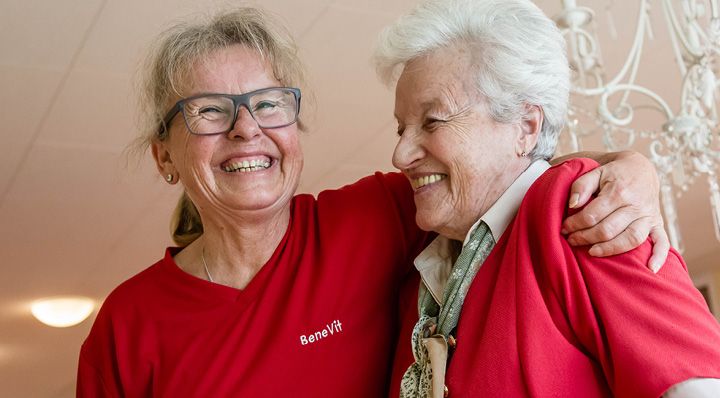 Pflegerin nimmt ältere Dame lachend in den Arm