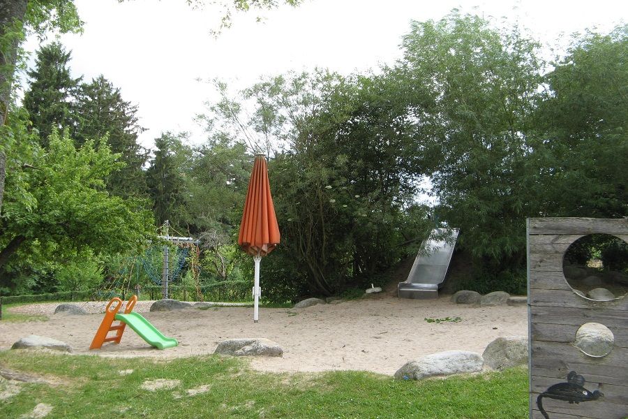 Garten mit Rutsche und rotem Sonnenschirm Kinderhaus Waldschule