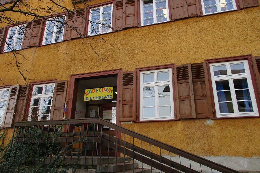 Eingang mit buntem Schild: Kinderhaus Kirchplatz