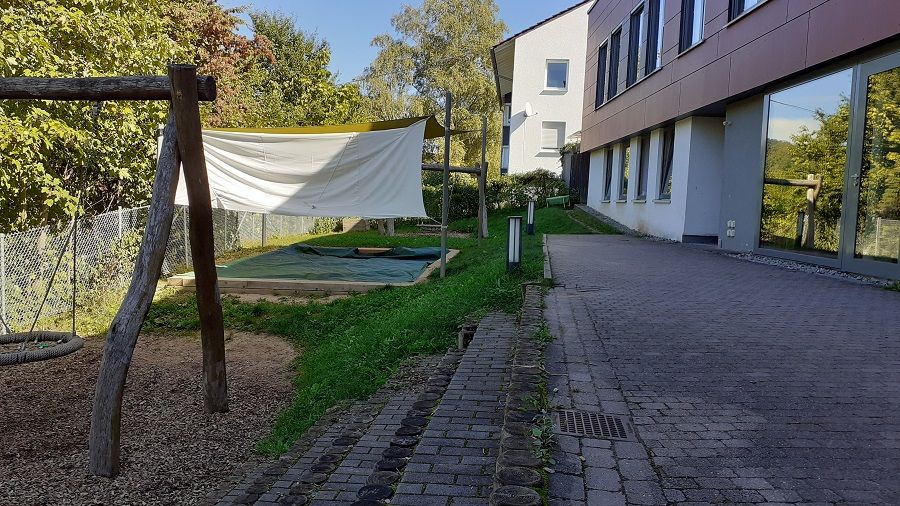 Garten eines Kindergartens mit Sandkasten und Schaukel