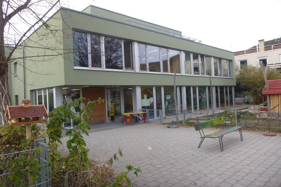 Außenansicht auf grüne Fassade mit vielen Fenstern des Kinderhauses Hirschau