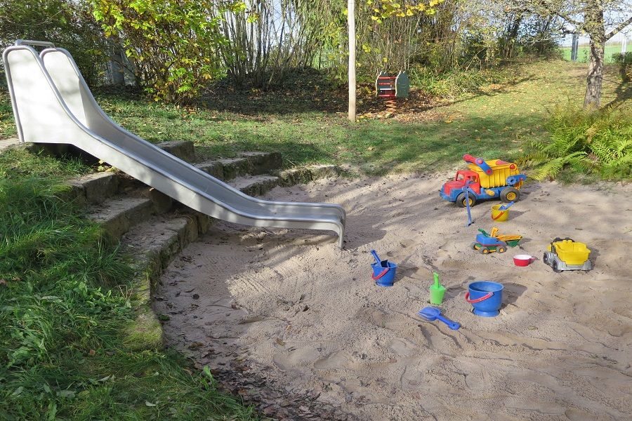 Garten mit Rutsche und Sandkasten mit Sandspielzeug