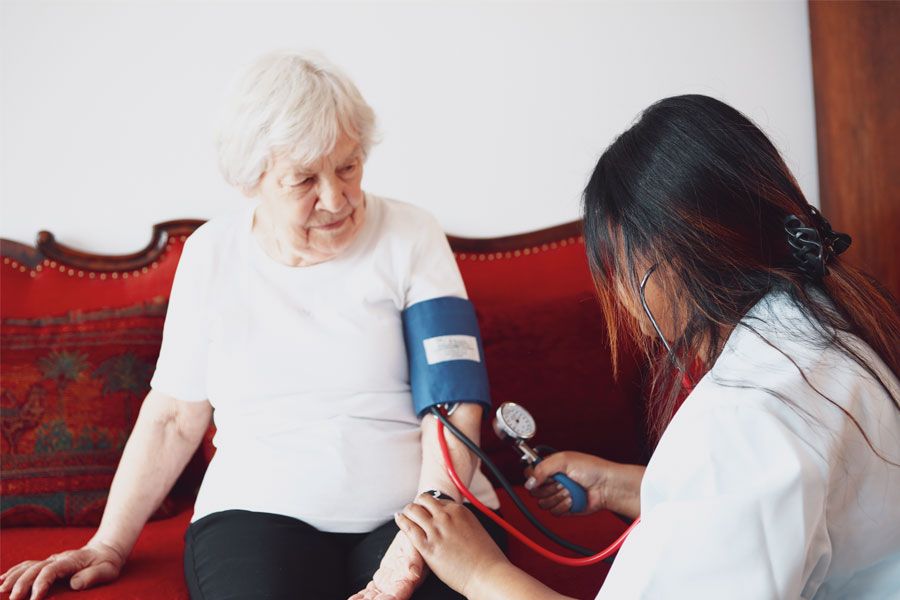 Pflegerin misst den Blutdruck einer alten Dame