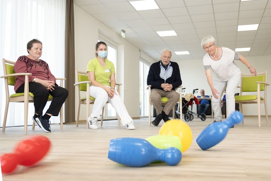 Ältere Menschen und Pflegerin kegeln